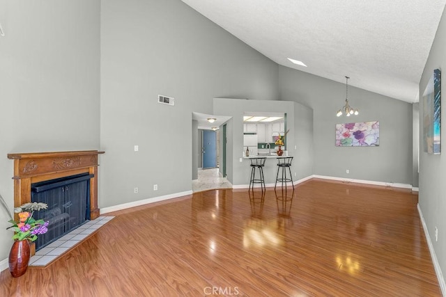 628 Daisy Ave Unit 420, Long Beach, CA 90802 - unfurnished living room with wood finished floors, a tiled fireplace, high vaulted ceiling, a chandelier, and baseboards