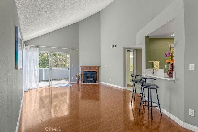 628 Daisy Ave Unit 420, Long Beach, CA 90802 - living room featuring wood finished floors, high vaulted ceiling, baseboards, a fireplace with flush hearth, and a textured ceiling