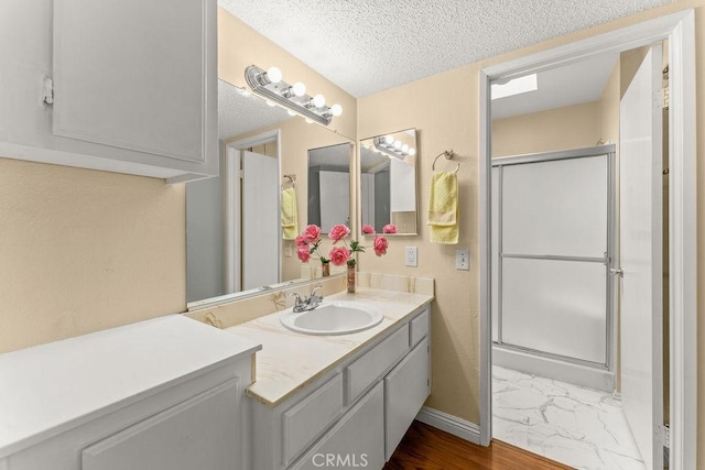 628 Daisy Ave Unit 420, Long Beach, CA 90802 - bathroom featuring a shower stall, vanity, a textured ceiling, marble finish flooring, and baseboards