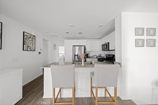 35753 Starling Ave Unit 1901, Murrieta, CA 92563 - kitchen with stainless steel appliances, a peninsula, wood finished floors, white cabinetry, and a kitchen bar