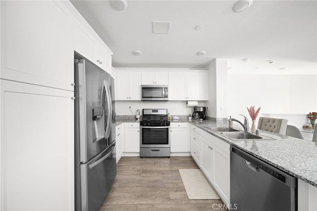 35753 Starling Ave Unit 1901, Murrieta, CA 92563 - kitchen with stainless steel appliances, a sink, light stone counters, white cabinets, and light wood-style flooring
