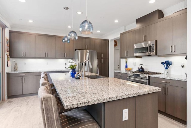 4304 Pacifica Way Unit 2, Oceanside, CA 92056 - kitchen featuring appliances with stainless steel finishes, a breakfast bar area, backsplash, light stone countertops, and pendant lighting