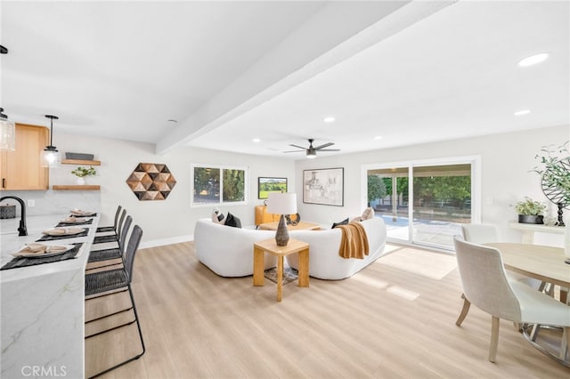 living area with light wood-style flooring, recessed lighting, ceiling fan, beam ceiling, and baseboards