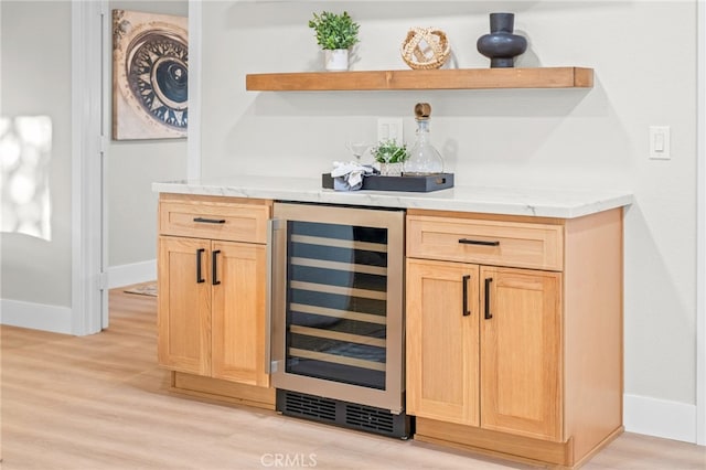 indoor dry bar featuring beverage cooler, light wood-type flooring, and baseboards