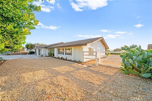 ranch-style home featuring fence, concrete driveway, a tile roof, stucco siding, and an attached garage