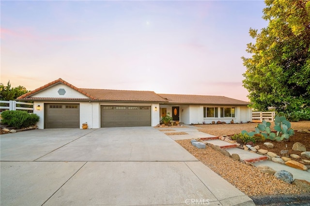 view of front of home with fence, a garage, driveway, and stucco siding
