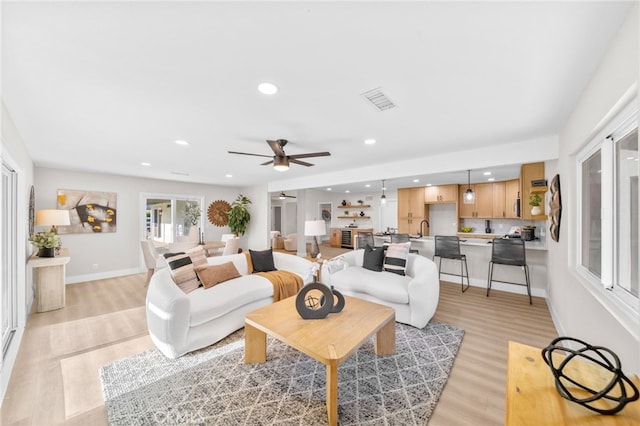 living room with light wood-style floors, a ceiling fan, baseboards, and recessed lighting