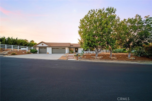 ranch-style house featuring fence, driveway, and an attached garage