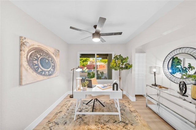 office space with light wood-style floors, a ceiling fan, and baseboards