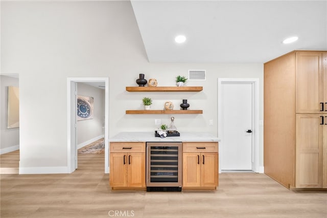 indoor bar with beverage cooler, light wood finished floors, baseboards, and recessed lighting
