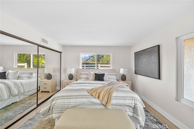 bedroom featuring baseboards, wood finished floors, and a closet