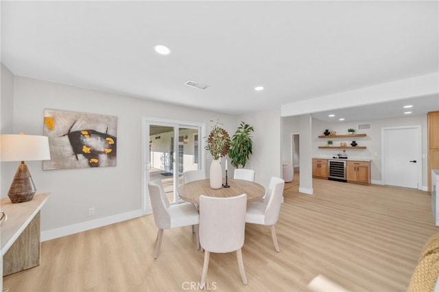 dining space featuring wine cooler, bar with sink, light wood finished floors, baseboards, and recessed lighting