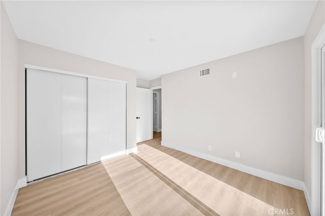 unfurnished bedroom with a closet, baseboards, and light wood-style floors