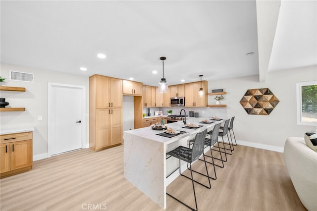 kitchen featuring open shelves, appliances with stainless steel finishes, light wood-style flooring, baseboards, and a peninsula