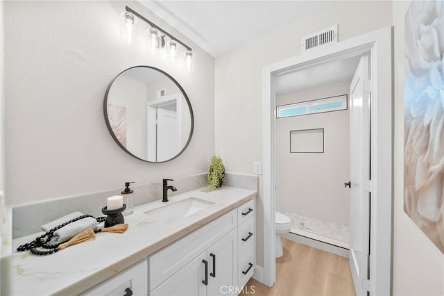 bathroom with toilet, a shower stall, wood finished floors, and vanity