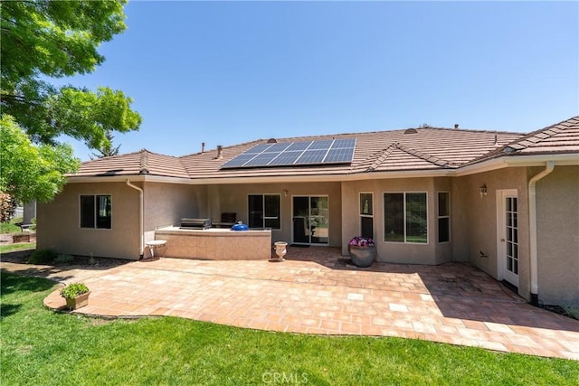 9539 Carmel Rd, Atascadero, CA 93422 - back of property with stucco siding, a tile roof, roof mounted solar panels, a patio, and an outdoor kitchen