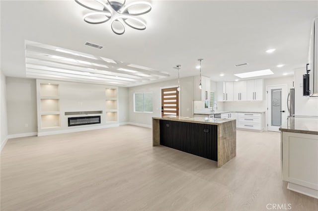 2202 Via Mariposa E Unit B, Laguna Woods, CA 92637 - kitchen featuring light wood finished floors, baseboards, built in features, light stone countertops, and stainless steel fridge