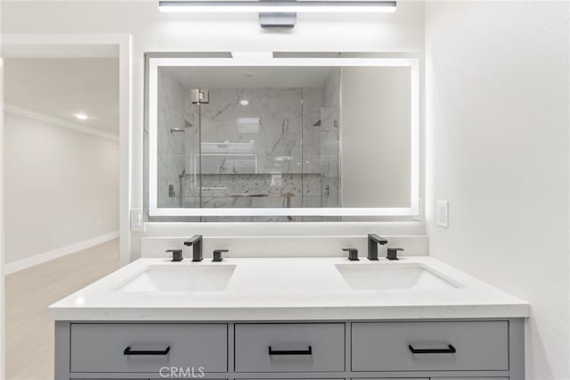 2202 Via Mariposa E Unit B, Laguna Woods, CA 92637 - bathroom featuring a marble finish shower, crown molding, double vanity, baseboards, and wood finished floors