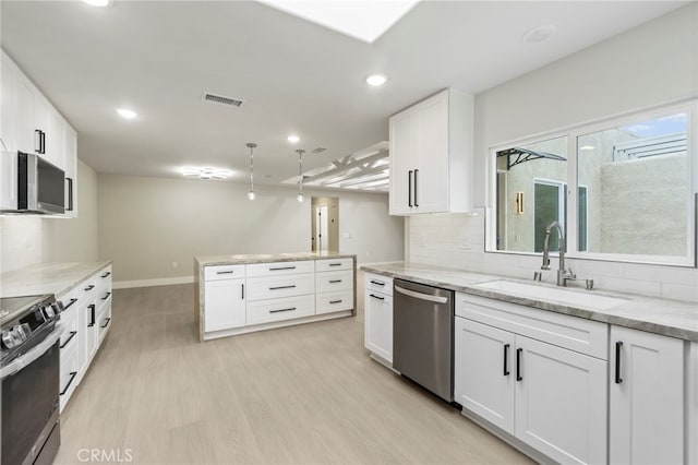 2202 Via Mariposa E Unit B, Laguna Woods, CA 92637 - kitchen with stainless steel appliances, a sink, light wood-type flooring, white cabinetry, and baseboards
