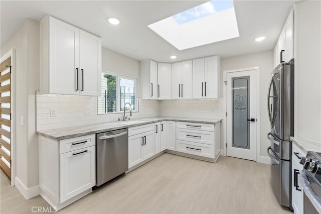 2202 Via Mariposa E Unit B, Laguna Woods, CA 92637 - kitchen with stainless steel appliances, a sink, light wood-style floors, light stone countertops, and baseboards