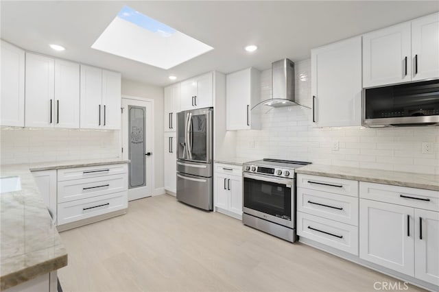 2202 Via Mariposa E Unit B, Laguna Woods, CA 92637 - kitchen with stainless steel appliances, wall chimney exhaust hood, a skylight, backsplash, and white cabinets