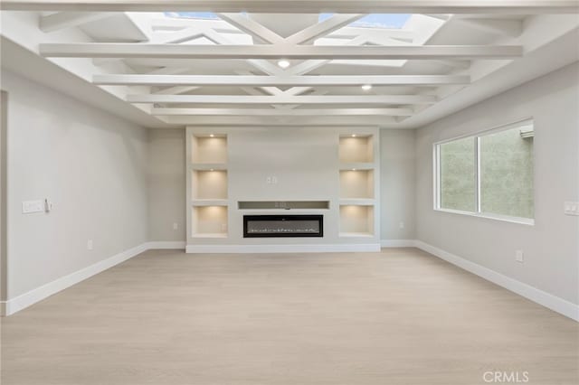 2202 Via Mariposa E Unit B, Laguna Woods, CA 92637 - unfurnished living room with light wood-type flooring, baseboards, built in shelves, beam ceiling, and a glass covered fireplace