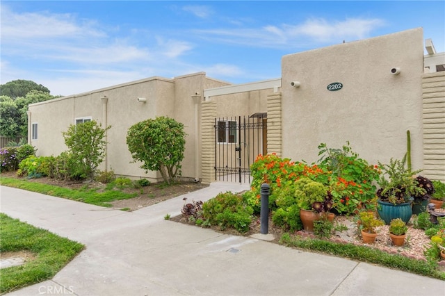 2202 Via Mariposa E Unit B, Laguna Woods, CA 92637 - view of front of house with a gate, stucco siding, and fence