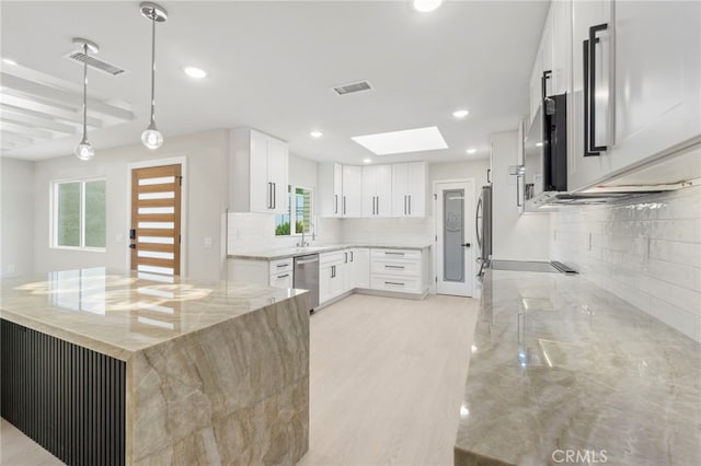 2202 Via Mariposa E Unit B, Laguna Woods, CA 92637 - kitchen with light stone counters, a skylight, tasteful backsplash, appliances with stainless steel finishes, and recessed lighting