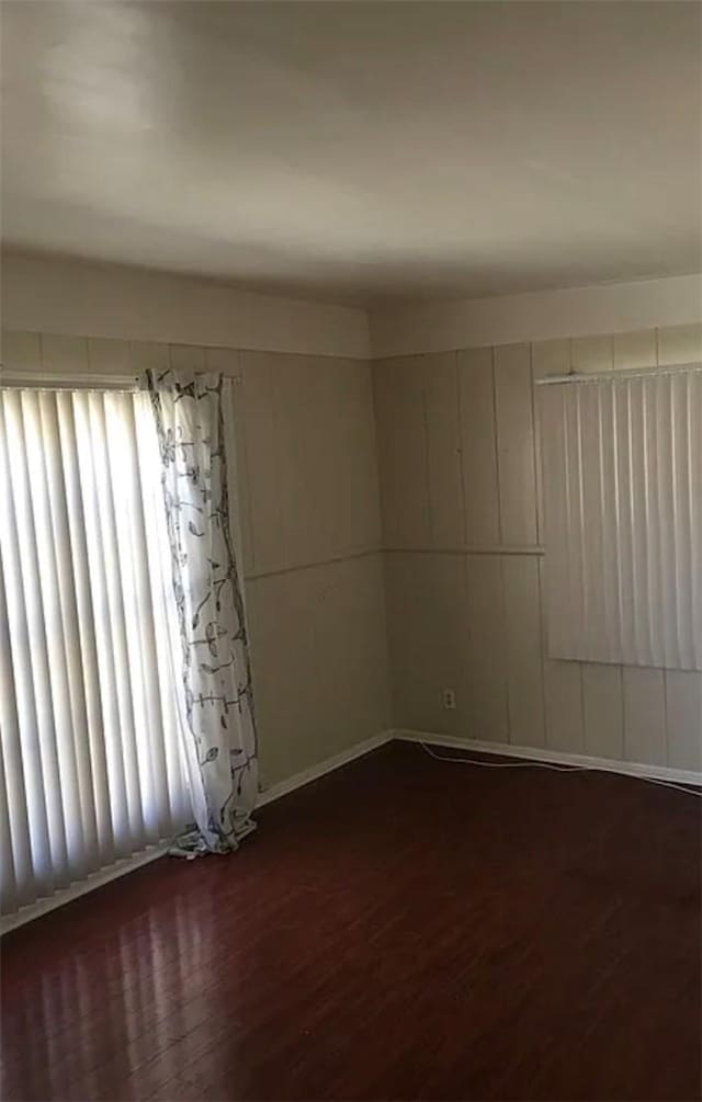 unfurnished room featuring dark wood-type flooring and baseboards