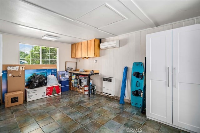 below grade area with a wall unit AC, heating unit, and dark stone finish floors