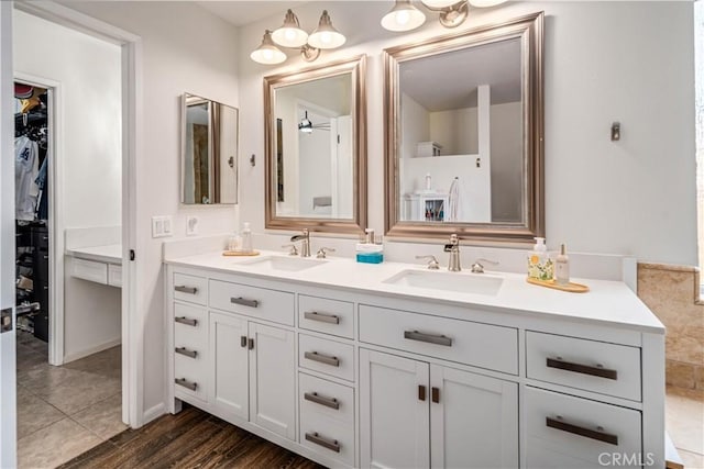 bathroom featuring double vanity, a spacious closet, and wood finished floors