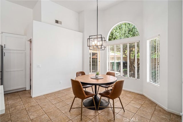 dining area featuring a high ceiling, a chandelier, light tile patterned flooring, and baseboards