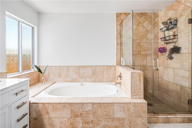 bathroom with a stall shower, a bath, and vanity