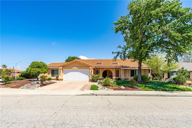 view of front facade with an attached garage, a tile roof, driveway, and stucco siding