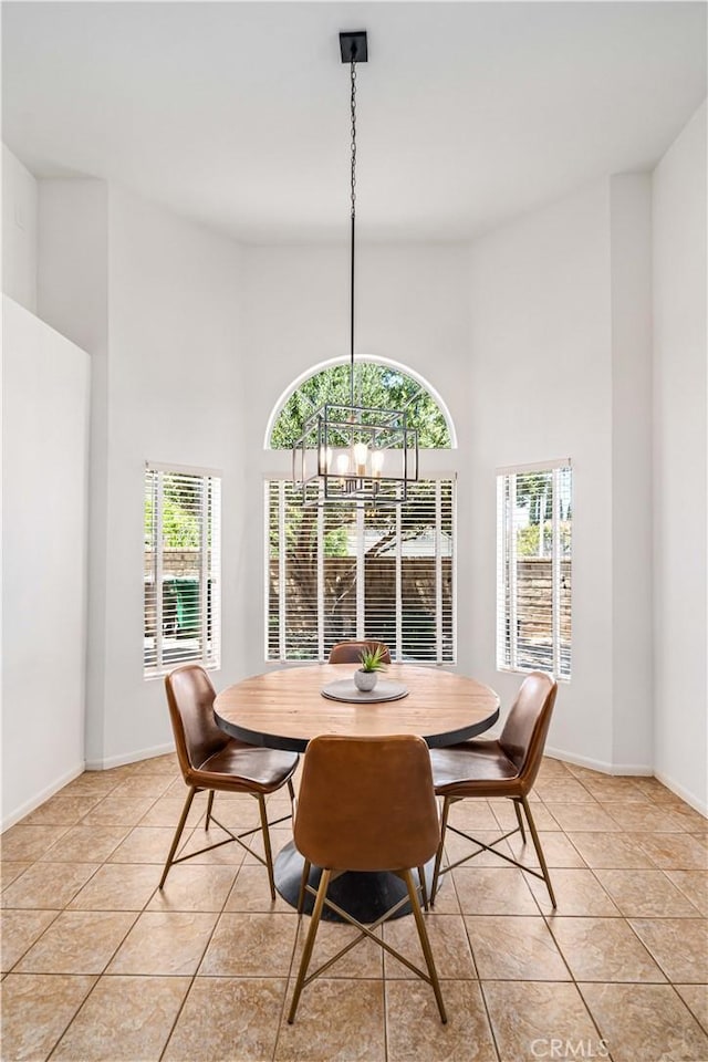 dining area featuring a chandelier, healthy amount of natural light, a towering ceiling, and light tile patterned flooring