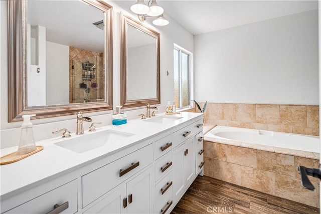 full bath featuring wood finished floors, a garden tub, tiled shower, and double vanity