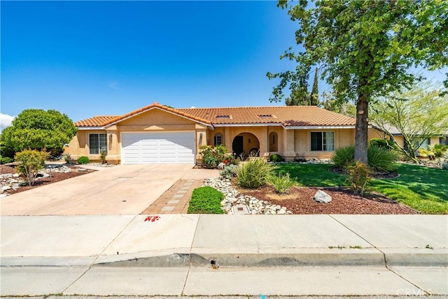 mediterranean / spanish-style house featuring an attached garage, a tile roof, concrete driveway, stucco siding, and a front lawn
