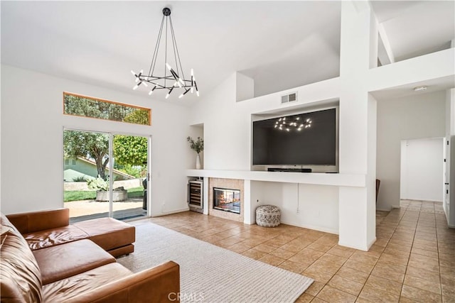living area featuring beverage cooler, high vaulted ceiling, a chandelier, a fireplace, and light tile patterned floors