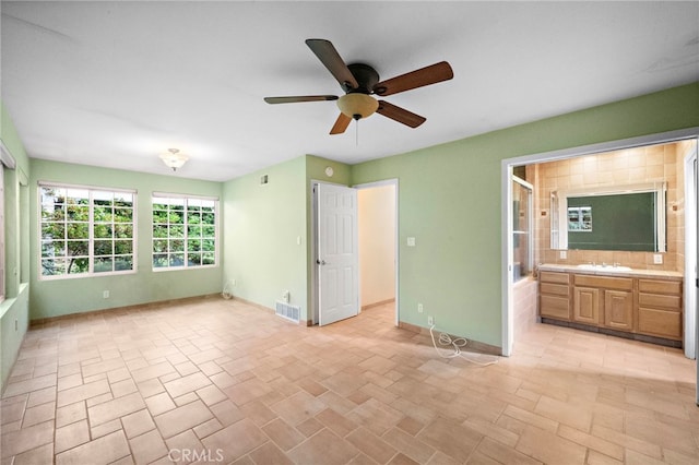 unfurnished bedroom with a sink, baseboards, ensuite bath, and a ceiling fan