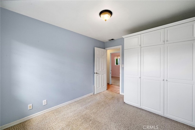 unfurnished bedroom with light colored carpet, baseboards, and a closet