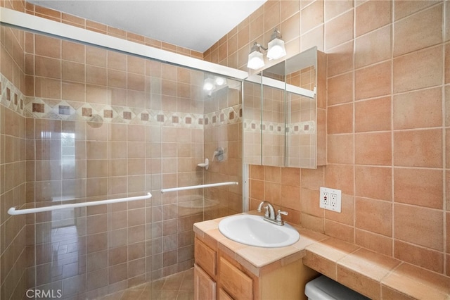 bathroom with vanity, tiled shower, tile walls, and tasteful backsplash