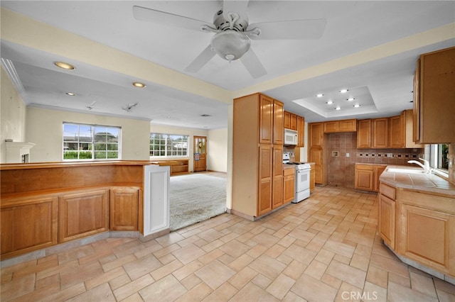 kitchen with white appliances, a tray ceiling, a sink, recessed lighting, and ceiling fan