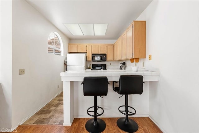25141 La Jolla Way Unit F, Laguna Niguel, CA 92677 - kitchen featuring freestanding refrigerator, black microwave, tile countertops, a peninsula, and light brown cabinetry