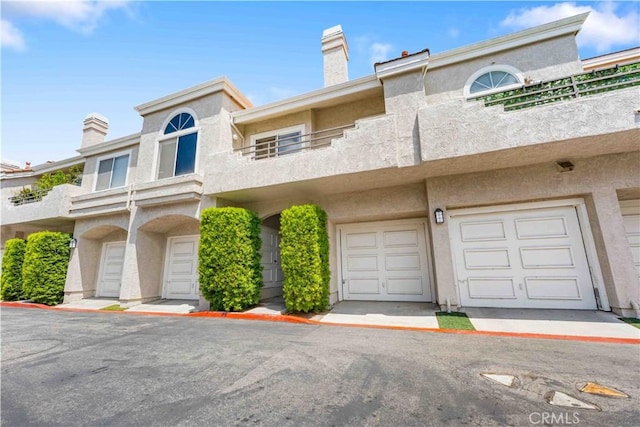 25141 La Jolla Way Unit F, Laguna Niguel, CA 92677 - view of front facade with stucco siding, a chimney, a balcony, and an attached garage
