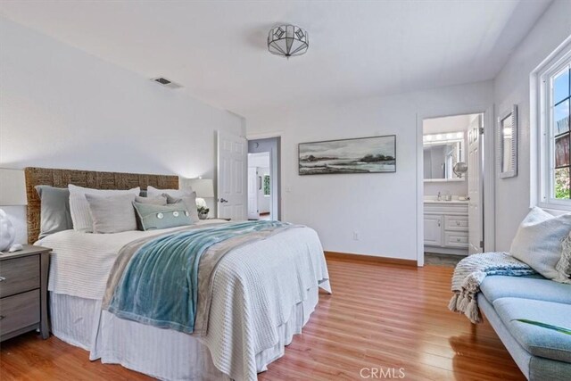 1360 El Moro Ave, Los Osos, CA 93402 - bedroom with light wood-style flooring, a sink, ensuite bath, and baseboards