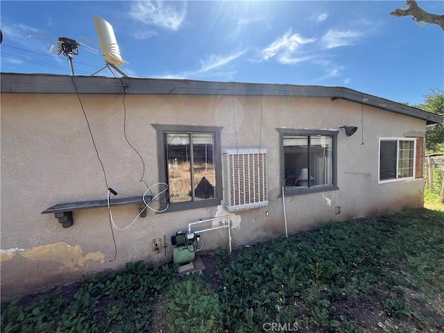 view of side of property featuring stucco siding and central AC