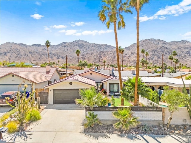 54415 Eisenhower Dr, La Quinta, CA 92253 - view of front facade with a fenced front yard, an attached garage, concrete driveway, stucco siding, and a mountain view