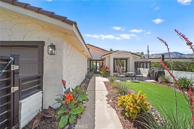 54415 Eisenhower Dr, La Quinta, CA 92253 - entrance to property featuring stucco siding, a lawn, a tiled roof, and a patio area