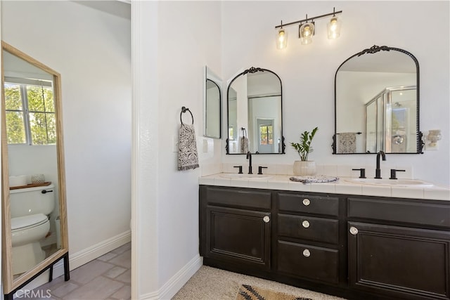 11934 Timber Mountain Ct, Rancho Cucamonga, CA 91739 - bathroom with baseboards, toilet, double vanity, and a stall shower