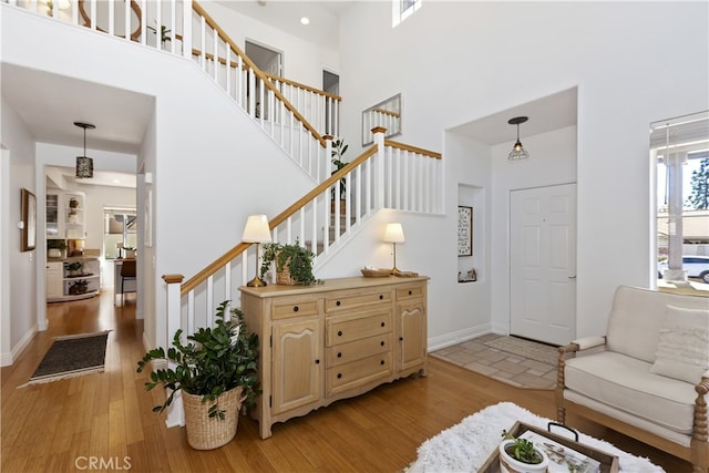 11934 Timber Mountain Ct, Rancho Cucamonga, CA 91739 - living area featuring a towering ceiling, light wood-type flooring, stairs, and baseboards